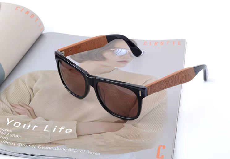 Black acetate sunglasses with a brown leather-wrapped temple detail