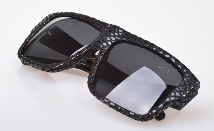 Black eyewear frame with an open textured leather covering across the front and temples