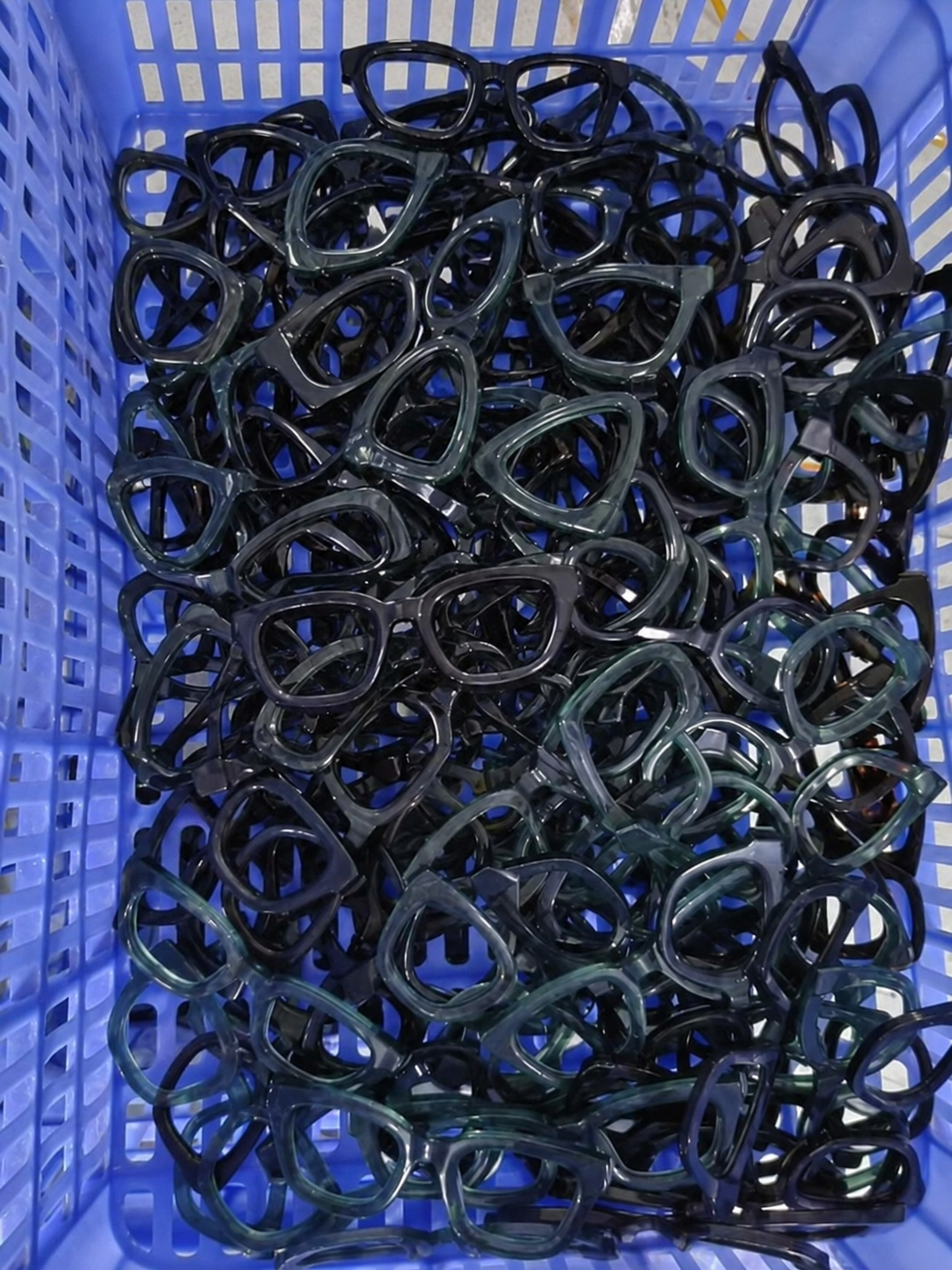 Mixed acetate frames piled together in a blue parts bin