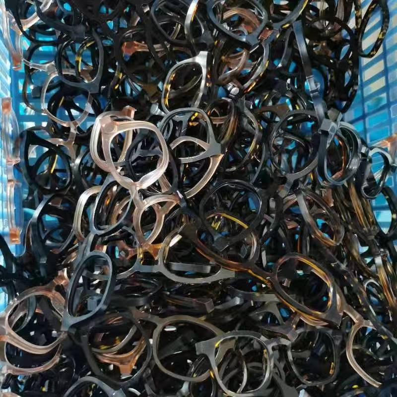 Mixed eyewear frames piled together in a blue parts bin