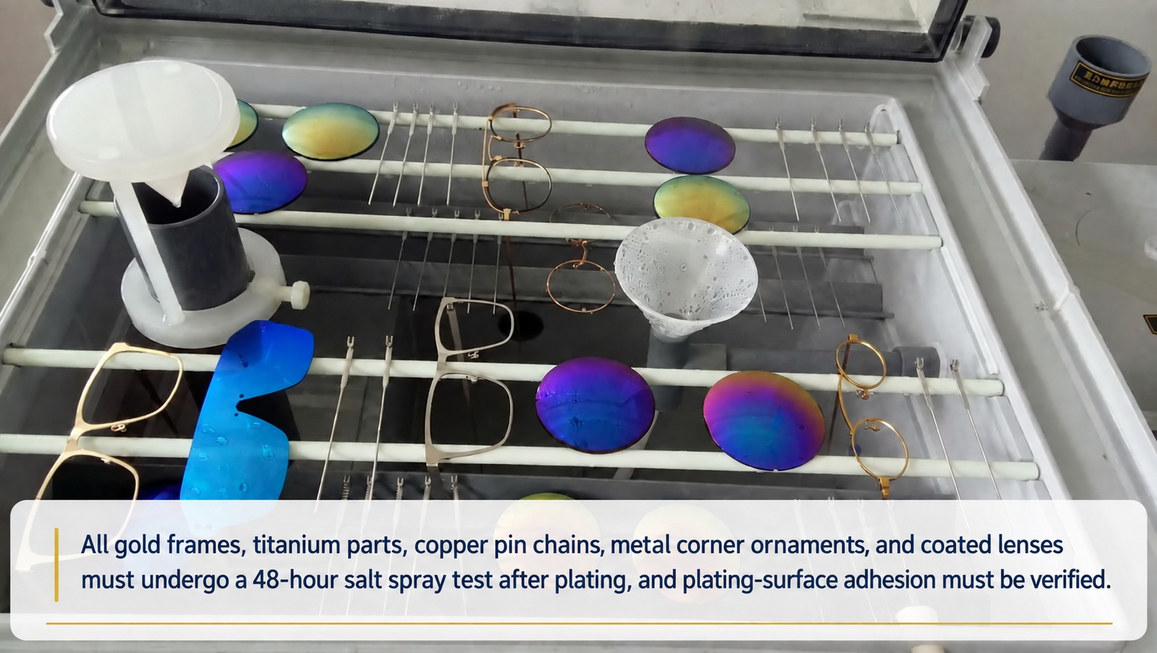 48-hour salt spray test chamber holding plated gold frames, titanium parts, copper pin chains, metal corner ornaments and coated lenses
